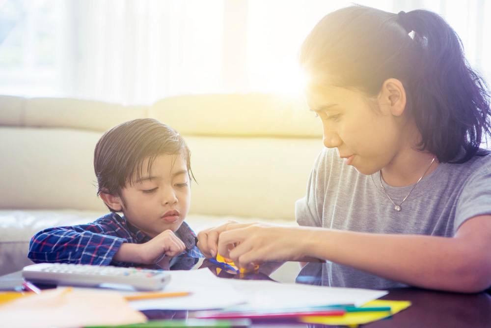 A very young school student learning from his tutor